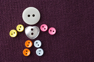 Funny character made of colorful sewing buttons with love heart shape central button. violet textured textile background. macro view, shallow depth of field photo