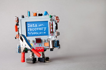 Data recovery concept. IT specialist robotic computer with red pliers, light bulb, warning message on blue display. Gray background, macro view photo.