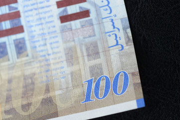Israeli banknote hundred shekels on a dark background close up
