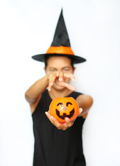 Young woman in witches hat and costume holding Jack pumpkin on a white background. Blur of Halloween Witch focus at Pumpkin.
