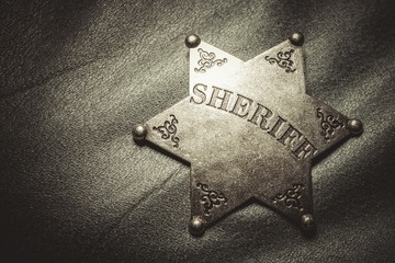 Sheriff badge on gray leather texture background. Macro shot.