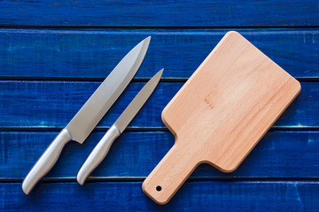 Knife and cutting board on blue rustic wooden table background