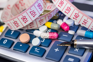 calculator with pills and measure tape. close up.