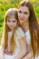 Beautiful mother and daughter in a blooming garden in the spring
