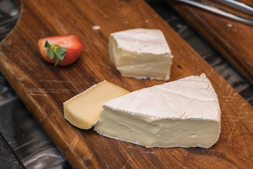 Variety of cheeses on a wooden board.