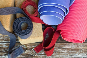 Yogi accessories: rolled exercise mat, cork blocks and strapson wooden background. Yoga props...