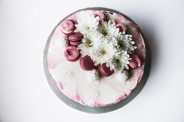 Wedding cake with white spring flowers and macaroon on top. Delicious pink cake