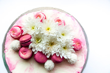 Wedding cake with white spring flowers and macaroon on top. Delicious pink cake isolated on white background.