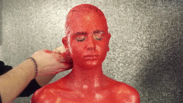 Makeup artist covering girl's neck with bright red paint