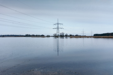 reflection of electricity pylon in water against sky 
