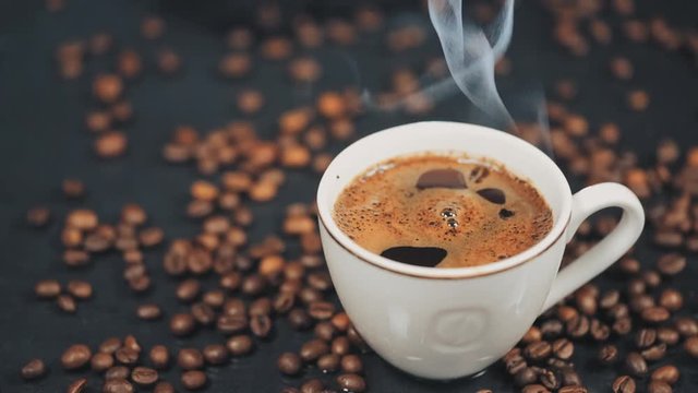 Cup of hot drink with steam over black background. Slow motion.