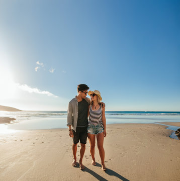Romantic young couple walking on sea shore