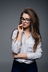 Closeup portrait of beautiful happy young woman with glasses near grey background