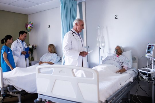 Male doctor interacting with senior patient in the ward