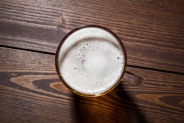 Mug of beer on an old wooden table. Top view