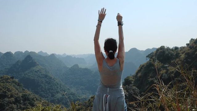 Attractive woman is rising her arms admiring beautiful views of Cat Ba Island from the observation deck at Ngu Lam peak.   Full HD slow motion stock footage. 