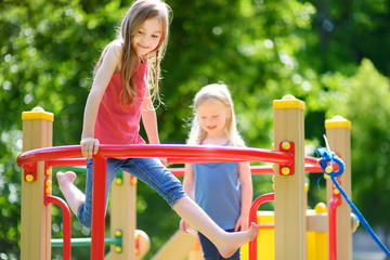 Fototapeta premium Two cute little girls having fun on a playground outdoors