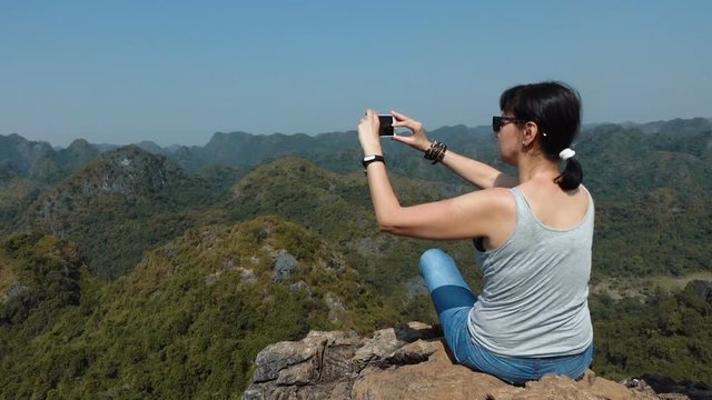Attractive woman taking pictures of beautiful views of Cat Ba Island from the observation deck at Ngu Lam peak.  Full HD slow motion stock footage. 
