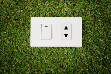 Electric plug outlet and switch on green grass nature background save eco environment concept