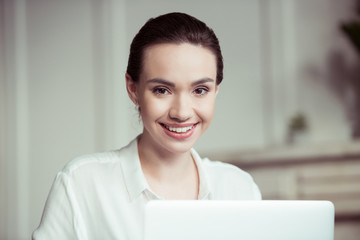 portrait of cheerful businesswoman working on laptop in office
