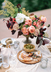 Wedding decor. Perfectly decorated holiday table for two with beautiful flower composition of fresh flowers, glasses for wine, cut jamon, green olives. concept of a festive dinner, outdoor.
