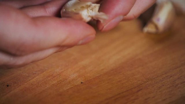 Close up cut garlic over wooden cutting board with knife, chile and pepper on background