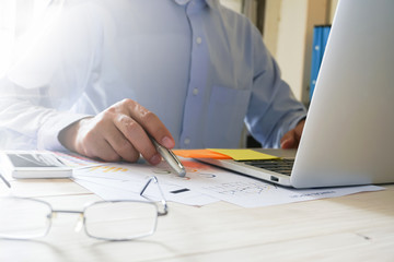 businessman hand working with laptop on wooden desk in office. can be used on an ad