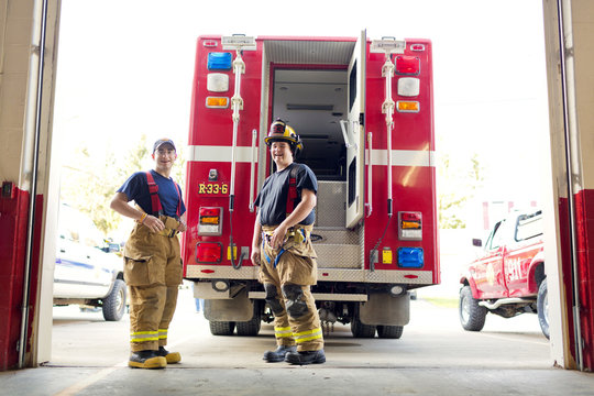 Two firemen standing in front of fire engine