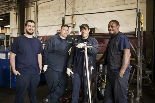 Portrait of four blue collar workers in garage