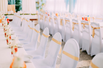 Decorative White Mantles And Colored Ribbons On Chairs At Festive Table.