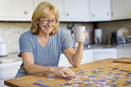 Senior woman putting puzzle together in kitchen