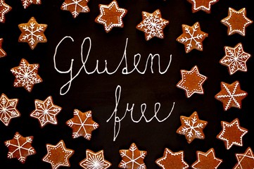 Gingerbread christmas cookies stars and snowflakes with white icing with text gluten free on black background