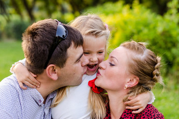 holiday outdoor portrait of happy family hugging and laughing at the picnic