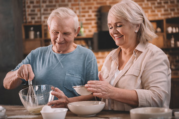 Smiling senior couple cooking together at kitchen table