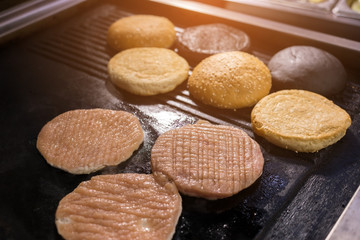 Pan with raw burger meat. Sliced sesame buns. Fry to the crisp.