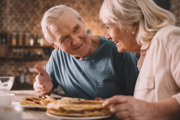 senior couple eating pancakes on kitchen at home