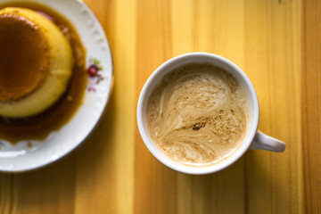One white cups with aroma refreshing coffee on a kitchen table, cream witfh heart on the top. Top wieu, blured caramel cream on the left.