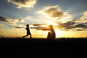 Silhouette of mother and kid. mother and daughter are playing happily together. The backdrop is the sunset.