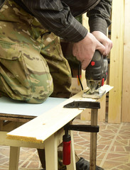 The worker by means of the tool performs work with wood