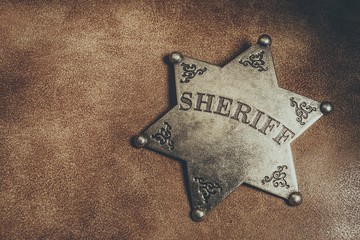 Sheriff badge on brown leather texture background. Macro shot.