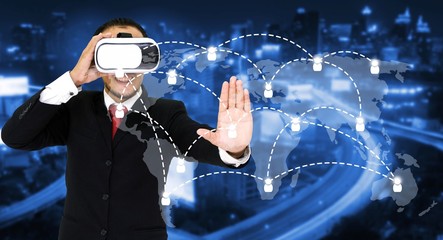 Young asian businessman wearing VR virtual reality headset, business and technology concept for future with world map social media connection on blurred night city background, color tone effect.