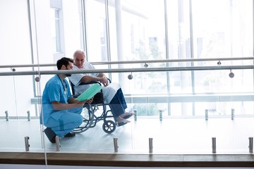 Fototapeta na wymiar Doctor interacting with male senior patient in passageway