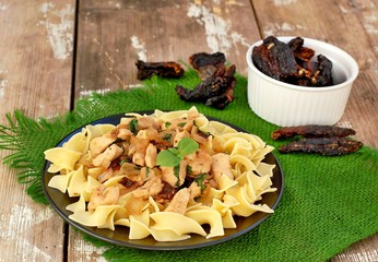 Italian food with pasta tagliatelle,sun dried tomatoes,basil and chicken meat on green cloth on wooden background