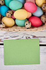 Easter eggs and blank card. Empty paper on wood background.