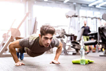 Fototapeta na wymiar Young fit hispanic man in gym doing push ups