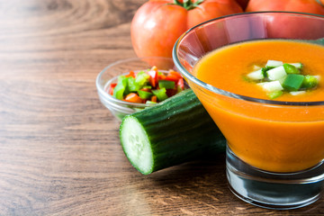 Traditional Spanish cold gazpacho soup and ingredients on wooden table
