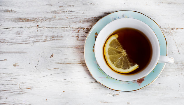 Cup of green tea with lemon on rustic wooden table
