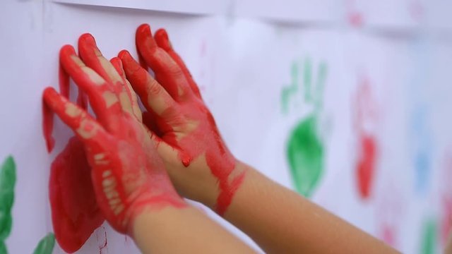 Close up of little cute child's hands making color handprints on the white wall in slow motion 50fps