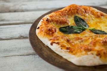 Italian pizza in a chopping board on a wooden plank