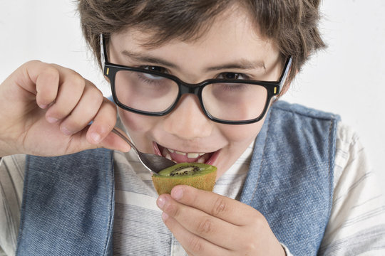 Ni&ntilde;o con gafas comiendo kiwi con una cuchara